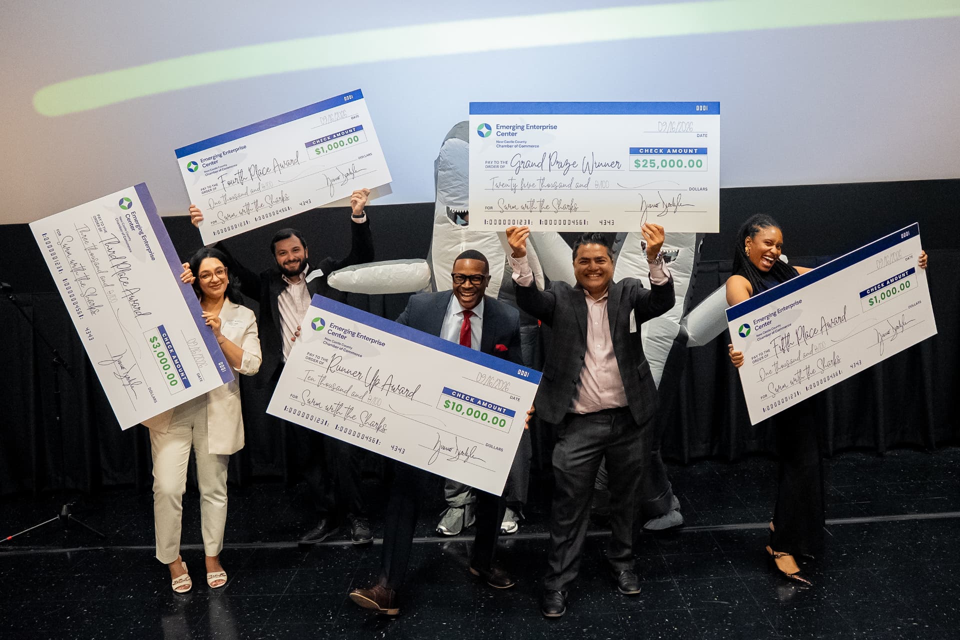 Five Emerging Enterprise Center award winners celebrating onstage with oversized checks