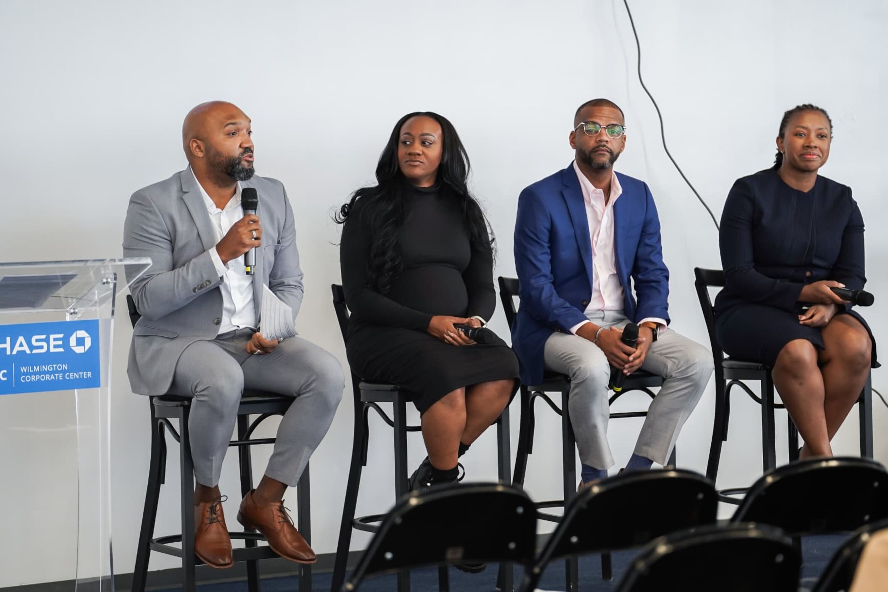 Four seated panelists, one speaking into a microphone