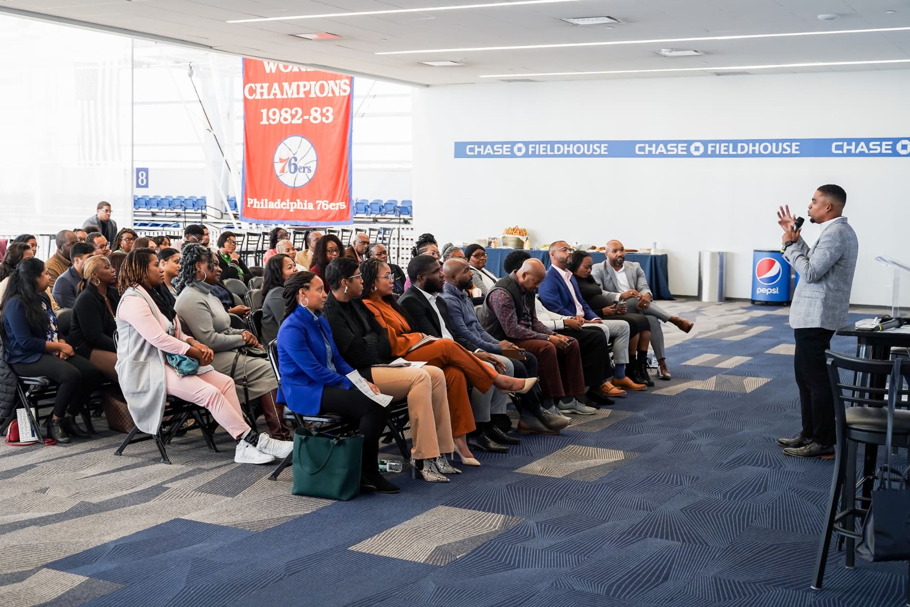 Speaker addressing a seated audience in a branded venue