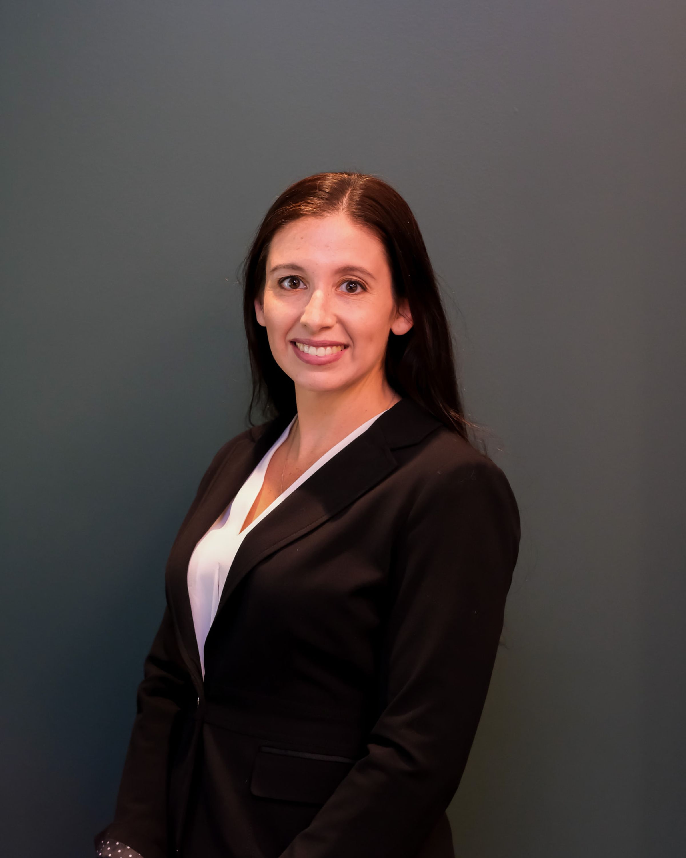 Portrait of a woman in a dark blazer against a gray background