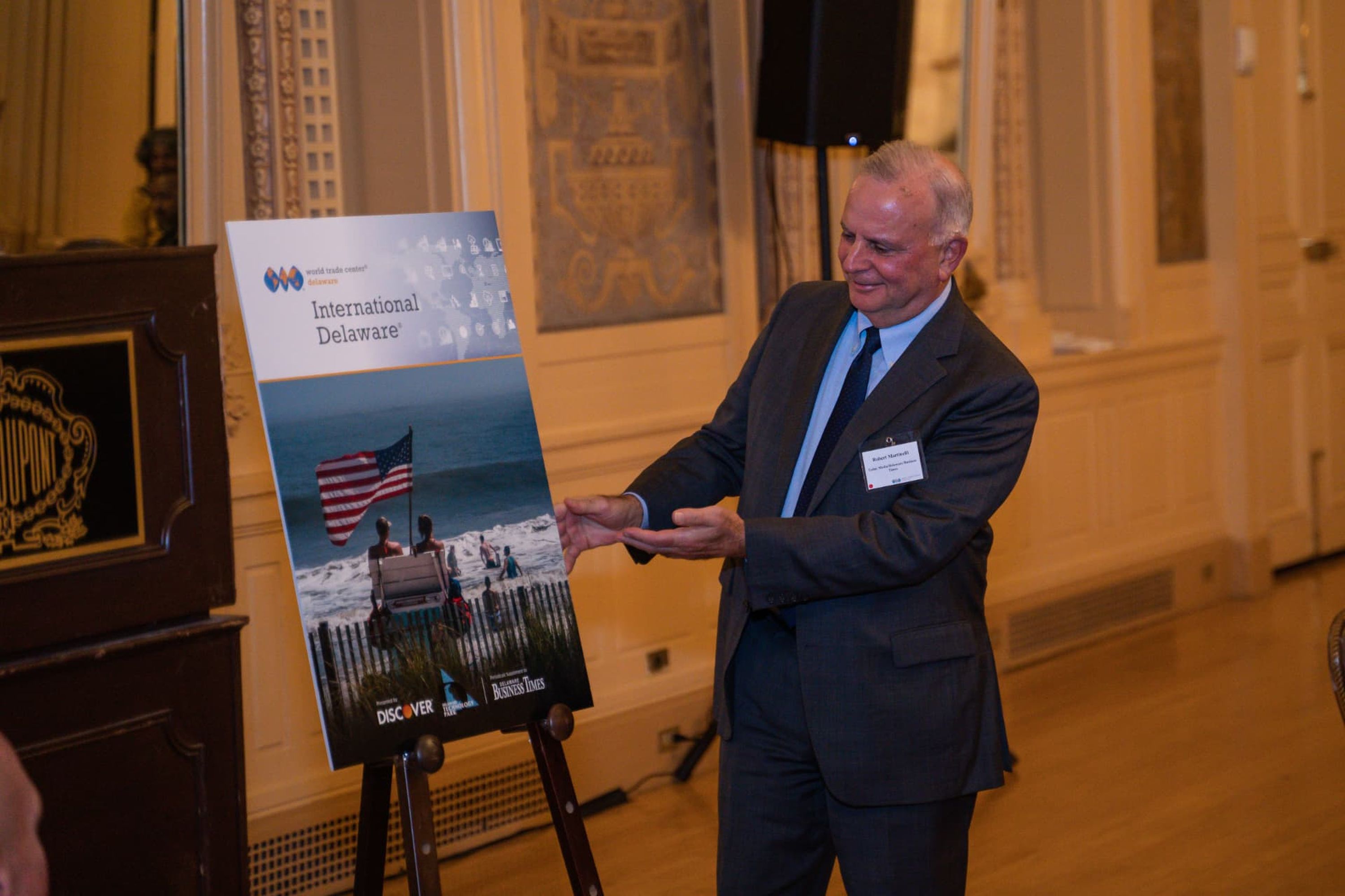 Man presenting a printed display beside a lectern