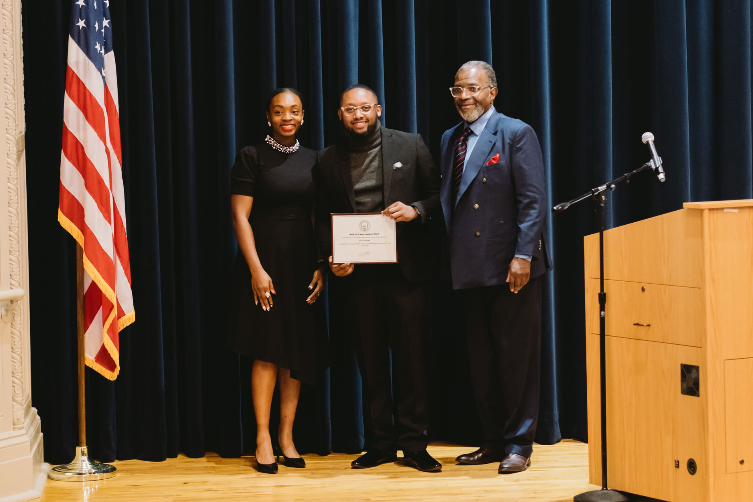 Three people at an award presentation, one holding a certificate