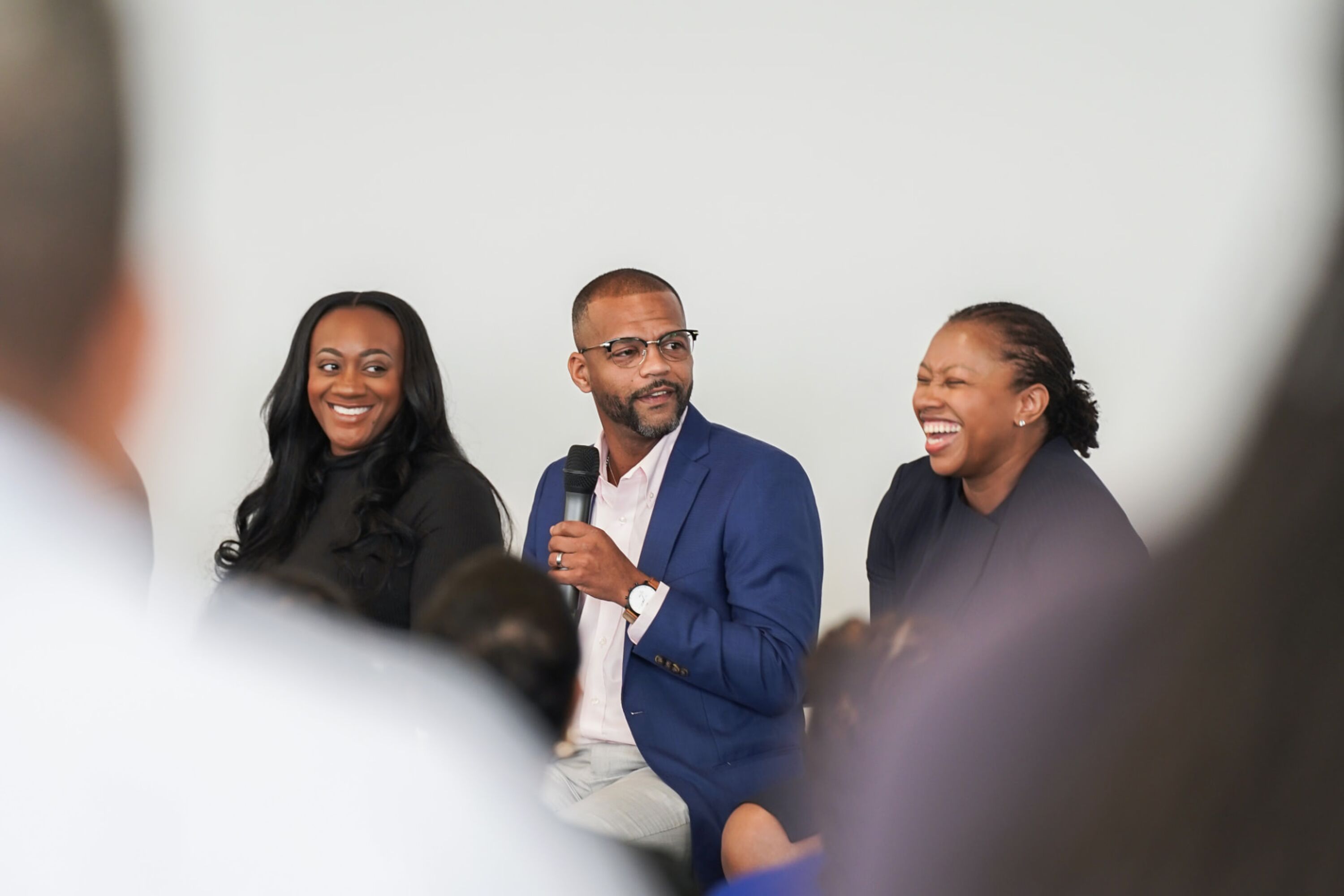 Three seated panelists, one speaking into a microphone